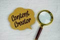 Content Creator text on sticky note with magnifying glass on concrete background Royalty Free Stock Photo
