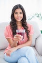 Content cute brunette sitting on couch holding glass of juice Royalty Free Stock Photo