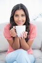 Content cute brunette sitting on couch holding mug Royalty Free Stock Photo
