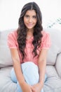 Content cute brunette sitting on couch looking at camera Royalty Free Stock Photo