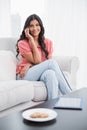 Content cute brunette sitting on couch phoning on smartphone Royalty Free Stock Photo