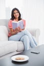 Content cute brunette sitting on couch reading Royalty Free Stock Photo
