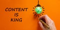 Content is king symbol. Businessman writing words `Content is king`, isolated on beautiful orange background. Light bulb icon. Royalty Free Stock Photo