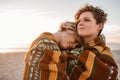 Content lesbian couple wrapped in a blanket at the beach Royalty Free Stock Photo