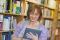 Content mature librarian using her tablet Royalty Free Stock Photo