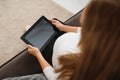 Content pregnant woman holding her tablet sitting on a couch in the living room at home