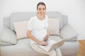 Content pregnant woman using her laptop smiling at camera