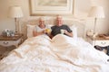 Content senior couple sitting in bed together drinking coffee Royalty Free Stock Photo