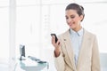 Content smart brown haired businesswoman looking at her mobile phone