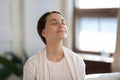 Content woman sitting on sofa with closed eyes breathing air Royalty Free Stock Photo