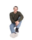 Contented casual young man sitting on the floor smiling to camera. Lifestyle full length portrait happy student guy isolated on Royalty Free Stock Photo