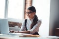 Cute brunette girl in eyeglasses typing and smiling