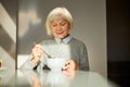 Contented elderly woman having breakfast in the sunlit kitchen
