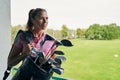 Contented female athlete holding a golf bag Royalty Free Stock Photo