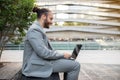 Contented modern businessman with topknot working on laptop outdoors Royalty Free Stock Photo