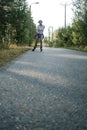 Contented, smiling woman is roller skating, at high speed, on the road among the trees, on a summer day. Active holidays Royalty Free Stock Photo