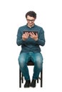 Contented young male student, seated on a chair, using a PC tablet for entertaining. Modern education concept, working and Royalty Free Stock Photo