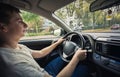 Contented young man driving car confident. Teenager driver enjoying the ride on the city streets, keeps hands on the steering Royalty Free Stock Photo