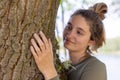 Contented young woman hugging a large tree with a blissful expression and her eyes closed in a concept of save the Royalty Free Stock Photo