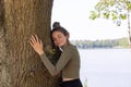 Contented young woman hugging a large tree with a blissful expression and her eyes closed in a concept of save the Royalty Free Stock Photo