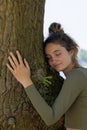 Contented young woman hugging a large tree with a blissful expression and her eyes closed in a concept of save the Royalty Free Stock Photo