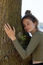 Contented young woman hugging a large tree with a blissful expression and her eyes closed in a concept of save the Royalty Free Stock Photo