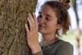 Contented young woman hugging a large tree with a blissful expression and her eyes closed in a concept of save the Royalty Free Stock Photo