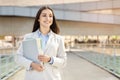 A contented young woman secretary, manager in a smart suit holds files, walking with confidence