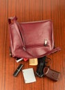 The contents of a woman's handbag with a cosmetic bag, a comb, lipstick and a gun on the table. Royalty Free Stock Photo