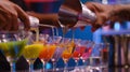 The contestants carefully mixing and layering different colorful liquids into their cocktail shakers