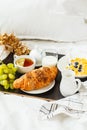 Continental breakfast in bed. Croissant, cornflakes, tea, milk and fruit on black tray Royalty Free Stock Photo