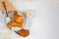 Continental breakfast, a cup of coffee with milk, two croissants, butter and orange jam on a wooden board, top view Royalty Free Stock Photo