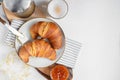 Continental breakfast, a cup of coffee with milk, two croissants, butter and orange jam on a wooden board, top view Royalty Free Stock Photo