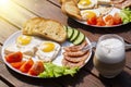 Continental breakfast set of eggs, ham, vegetables and cheese. Bread and coffee on a wooden table. Breakfast for two Royalty Free Stock Photo