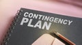 Contingency Plan words on upper page of copybook, pen and pink leather wallet. business crisis concept