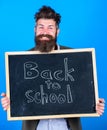 Continue your education with us. Teacher bearded man stands and holds blackboard with inscription back to school blue