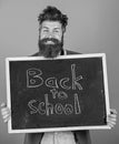 Continue your education with us. Teacher bearded man stands and holds blackboard with inscription back to school blue