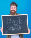 Continue your education with us. Teacher bearded man stands and holds blackboard with inscription back to school blue