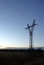 Contour of high-voltage strong power line metal prop with electrical wires in twilight on beautiful rural sunset Royalty Free Stock Photo