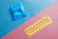 Contraception pills and condom on blue and pink background. Royalty Free Stock Photo