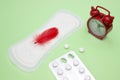 Contraceptive, birth control hormone pills. Menstruation pad, red feather, alarm clock and pills. White pharmaceutical tablets. Me