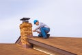 Contractor Builder on roof with blue hardhat caulking chimney Royalty Free Stock Photo