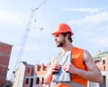 Contractor control according to plan. Man orange vest and helmet works at construction site. Control construction Royalty Free Stock Photo