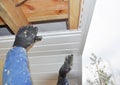 Contractor installing soffit boards on house roofing construction.