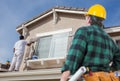 Contractor Overlooking Painter Painting House