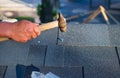 Contractor repair corner bitumen roof shingles with hammer and nails