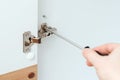 Man assembling white wooden furniture with a screwdriver. Housing furniture theme