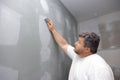 A contractor is sanding the wall after putting up putty as part of a renovation project for an apartment