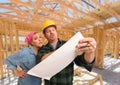 Contractor Showing Plans to Woman On Site Inside New Home Construction Framing. Royalty Free Stock Photo