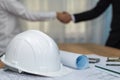 Contractor. white safety helmet on workplace desk with construction worker team hands shaking Royalty Free Stock Photo